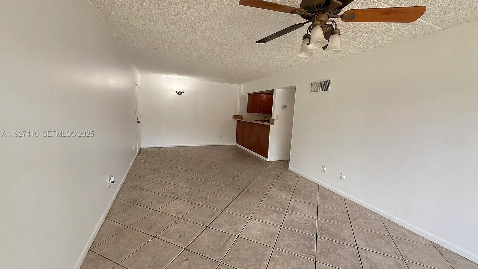An open living area features beige tile flooring, white walls, and a ceiling fan — 5855 Washington St # 91, Hollywood FL 33023, HOLLYWOOD, FL