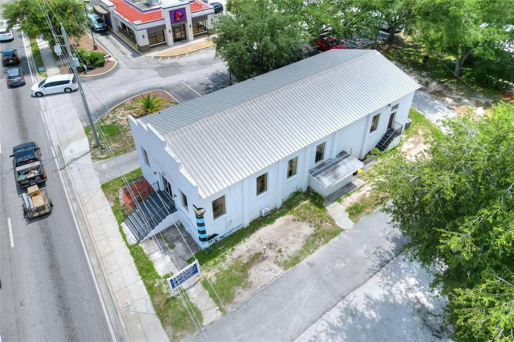 An aerial view shows a white commercial building with a metal roof next to a road — 1649 3RD STREET SW, WINTER HAVEN, FL