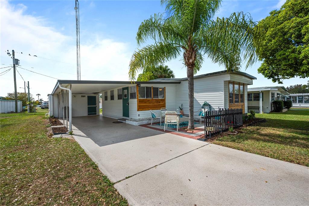 A single-story mobile home features a carport, a palm tree, and a small front patio — 5345 JO STREET, ZEPHYRHILLS, FL