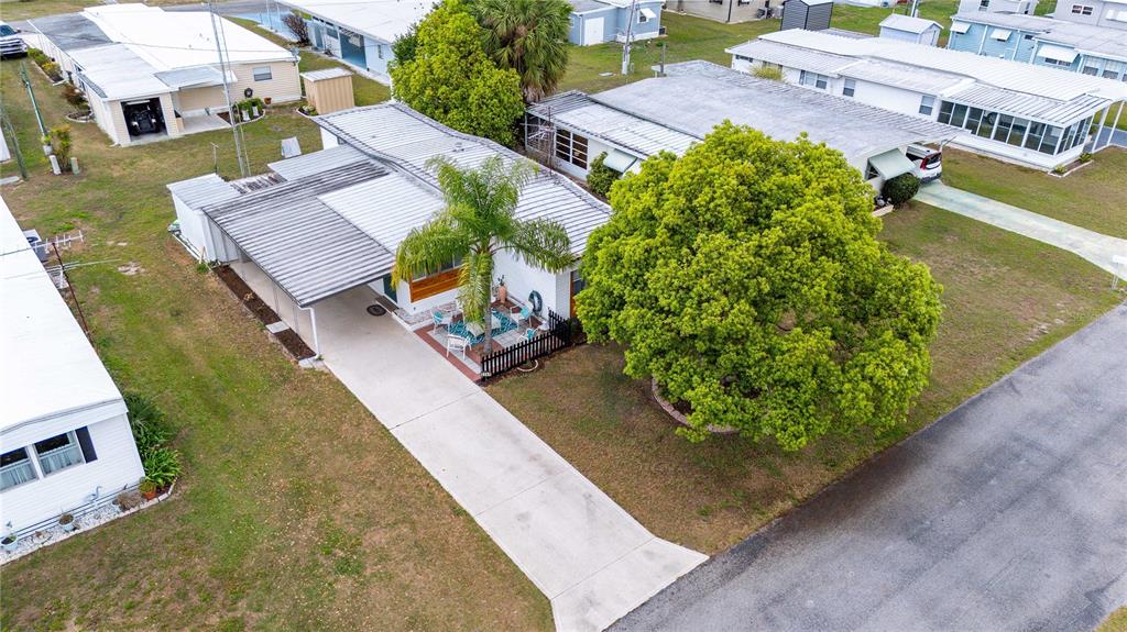 An aerial view shows a mobile home with a carport, patio, and large shade tree — 5345 JO STREET, ZEPHYRHILLS, FL