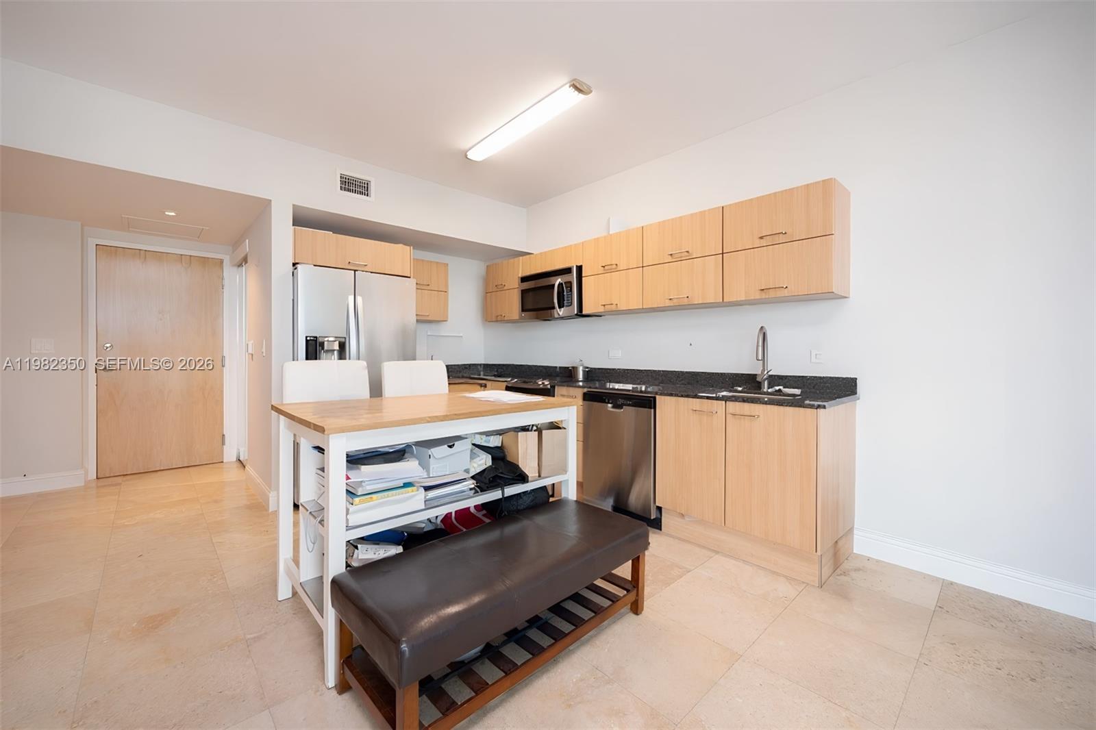 A kitchen features light wood cabinets, dark granite countertops, stainless steel appliances, and a dining island — 350 S MIAMI # 1709, Miami FL 33130, MIAMI, FL