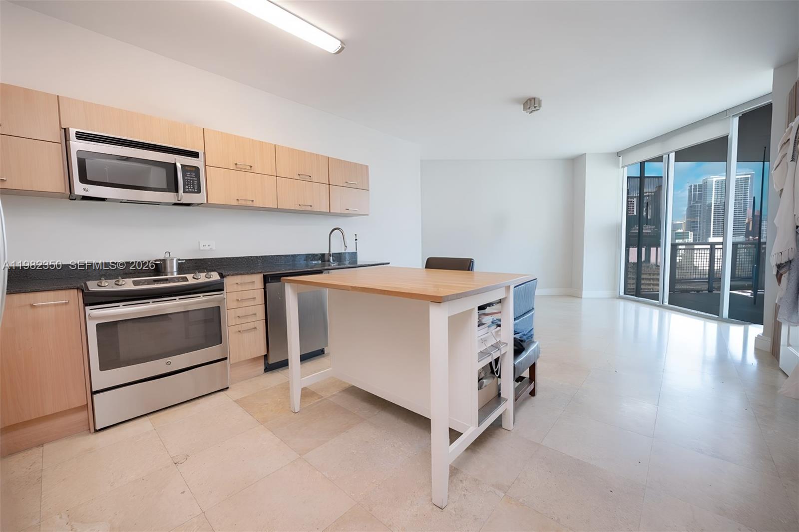 A kitchen with light wood cabinets, stainless steel appliances, and a central island faces windows — 350 S MIAMI # 1709, Miami FL 33130, MIAMI, FL