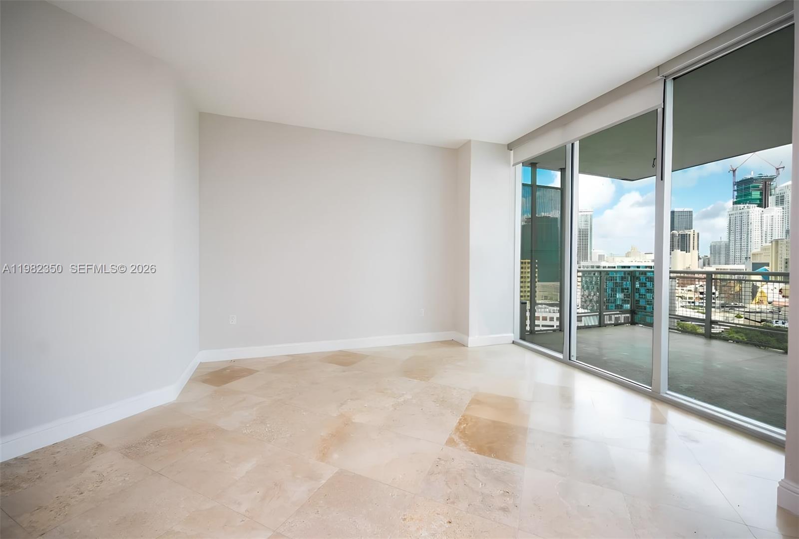 An empty room with light-colored tile flooring and floor-to-ceiling windows overlooking a city skyline — 350 S MIAMI # 1709, Miami FL 33130, MIAMI, FL