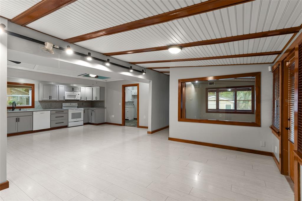An open-concept room features light wood-look flooring, a white paneled ceiling, and a kitchen area — 10519 BRIDGEWOOD DRIVE, RIVERVIEW, FL