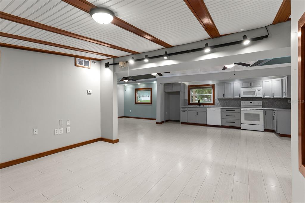 An open-concept kitchen and living area features light wood-look flooring and a white beamed ceiling — 10519 BRIDGEWOOD DRIVE, RIVERVIEW, FL
