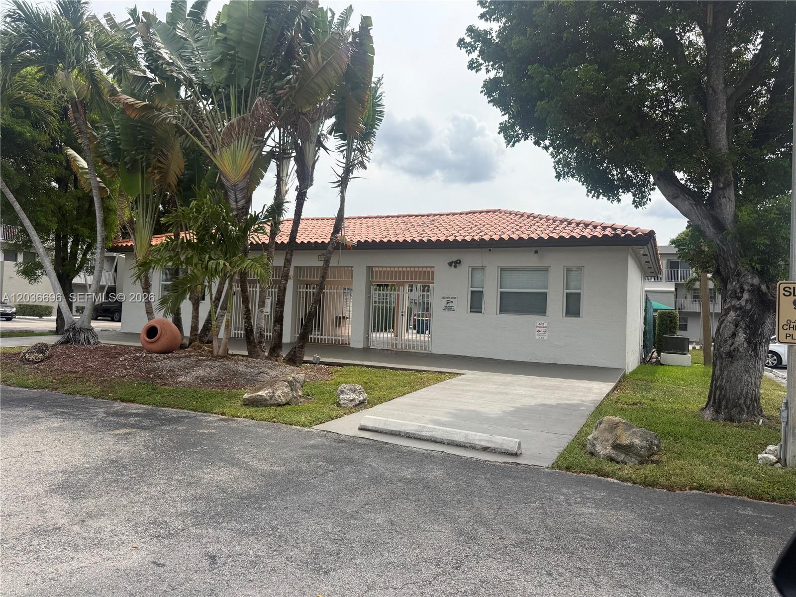A single-story building with a tiled roof, white stucco walls, and a gated entrance — 7510 SW 152nd Ave # B202, Miami FL 33193, MIAMI, FL