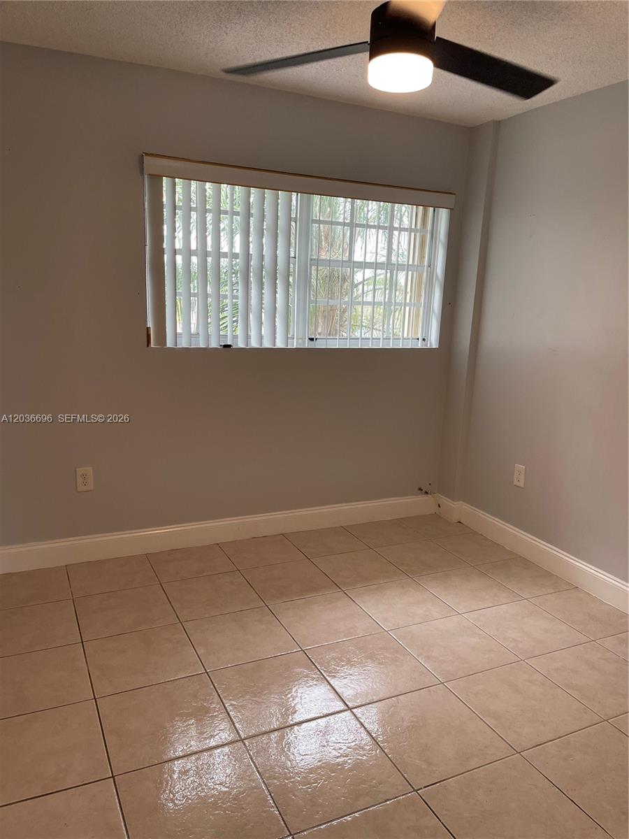 A room with light-colored tile flooring, a ceiling fan, and a window with vertical blinds — 7510 SW 152nd Ave # B202, Miami FL 33193, MIAMI, FL