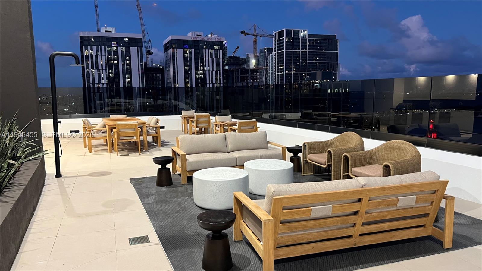 An outdoor rooftop terrace features wooden patio furniture, lounge seating, and views of city skyscrapers — 225 N Miami Ave # 312, Miami FL 33128, MIAMI, FL
