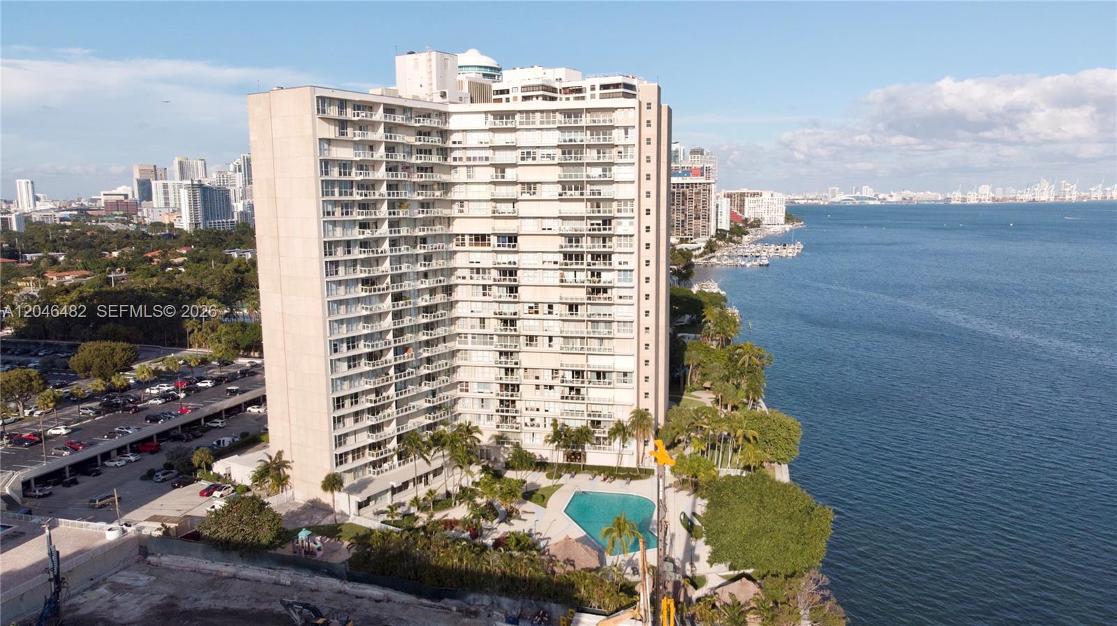 An aerial view shows a tall residential building with a pool beside a bay — 2451 Brickell Ave # 19B, Miami FL 33129, MIAMI, FL