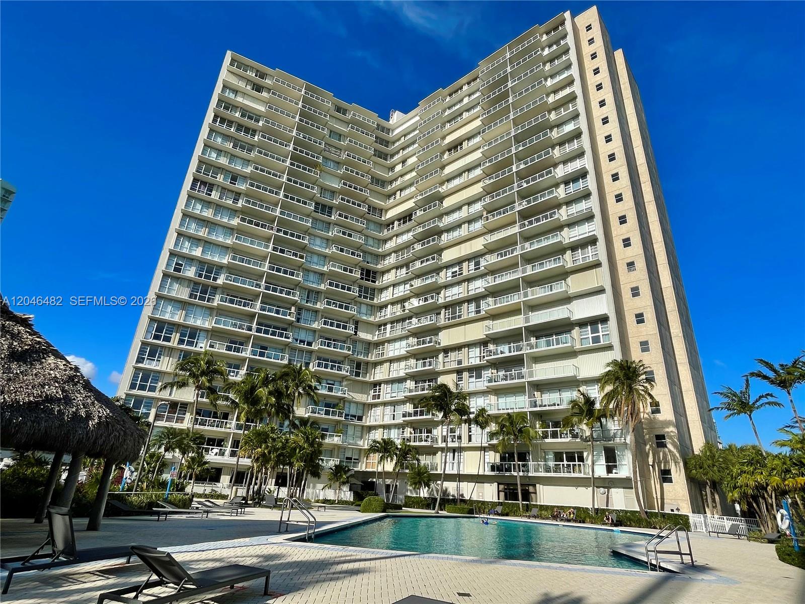 A tall residential building with many balconies overlooks a swimming pool and palm trees — 2451 Brickell Ave # 19B, Miami FL 33129, MIAMI, FL