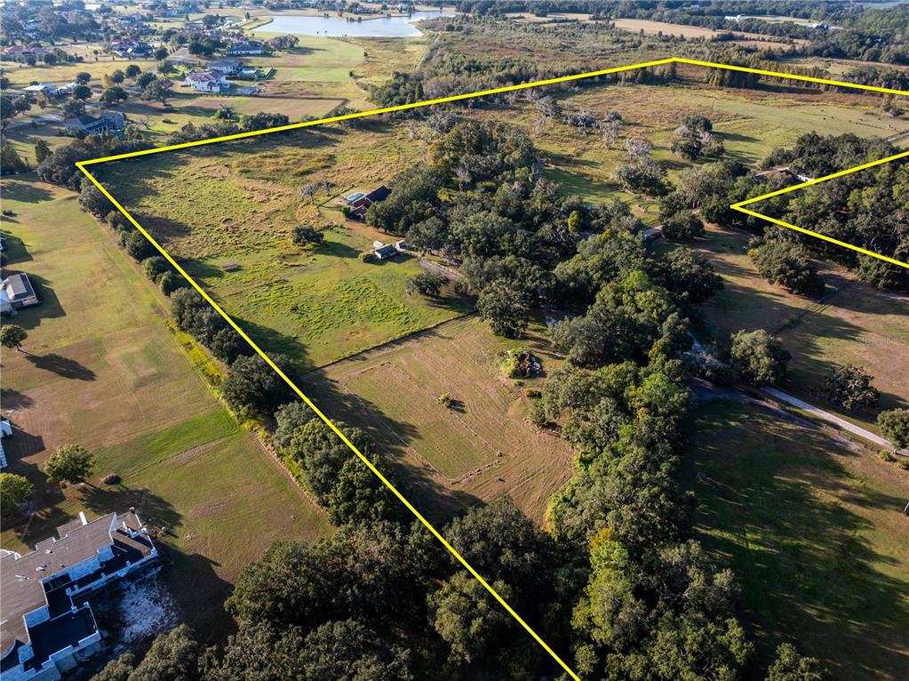 An aerial view shows a large, grassy rural property outlined in yellow with scattered trees — 12537 TOMAR DRIVE, THONOTOSASSA, FL