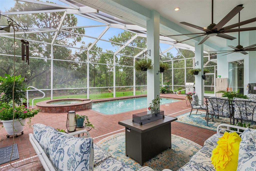 A screened-in patio features a brick floor, a swimming pool, a hot tub, and furniture — 8 COSMOS COURT E, HOMOSASSA, FL