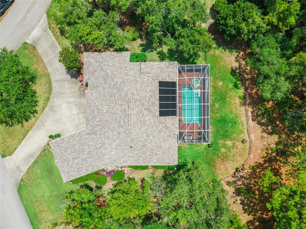 An aerial view of a house with a shingled roof, pool enclosure, and driveway — 8 COSMOS COURT E, HOMOSASSA, FL