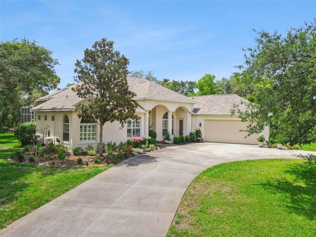 A single-story stucco house with an arched entryway and a concrete driveway — 8 COSMOS COURT E, HOMOSASSA, FL