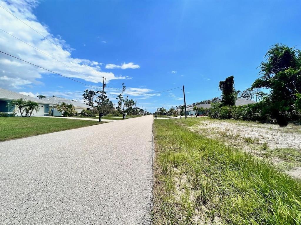 A paved residential street stretches into the distance between houses and vacant lots — 230 FAIRWAY ROAD, ROTONDA WEST, FL