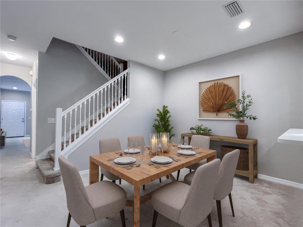A dining room features a wooden table with six chairs, a staircase, and wall art — 267 CAPE HARBOUR LOOP UNIT 103, BRADENTON, FL