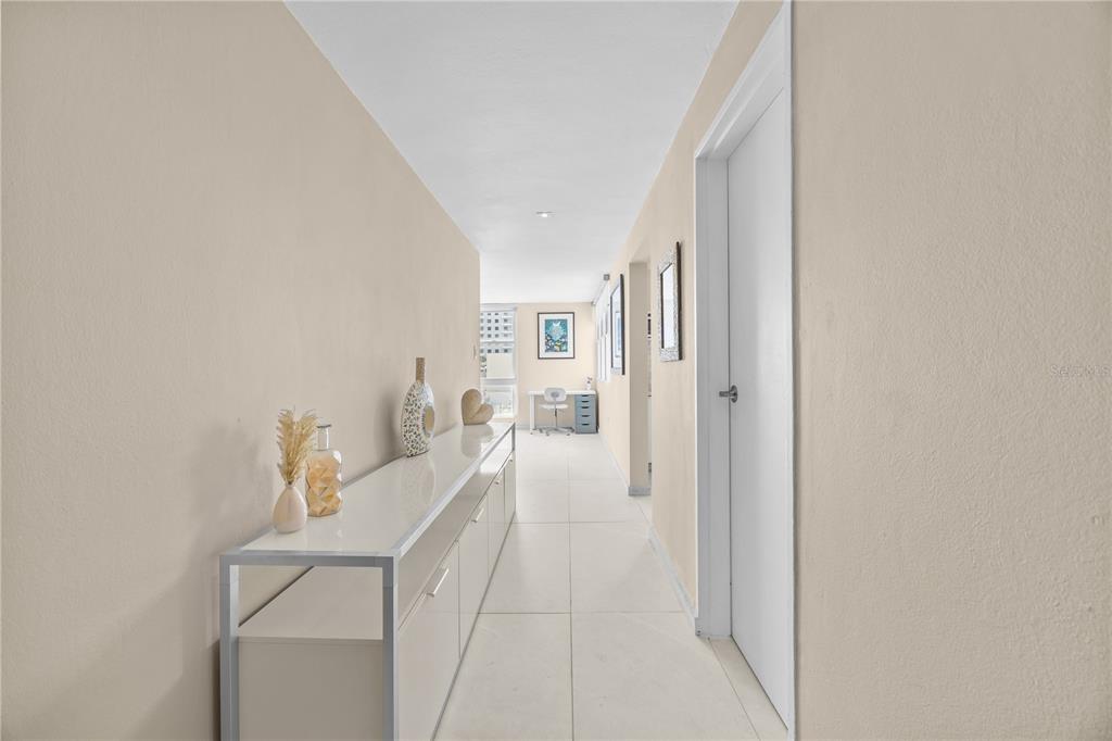 A long, white-tiled hallway features a modern console table and a view toward a desk — 1035 AVE ASHFORD UNIT 302, SAN JUAN, PR