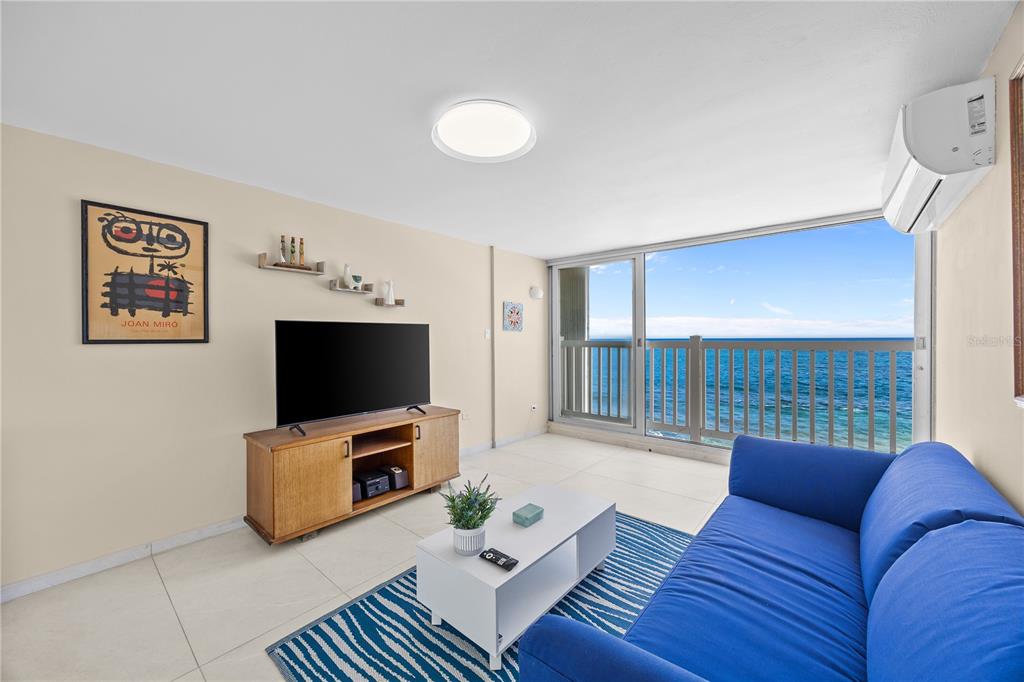 A living room features a blue sofa, a television on a wooden stand, and a balcony — 1035 AVE ASHFORD UNIT 302, SAN JUAN, PR
