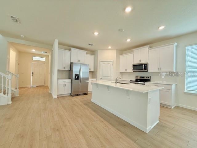 A modern kitchen features white cabinets, stainless steel appliances, and a large central island — 16827 HOBE SOUND COURT, WINTER GARDEN, FL
