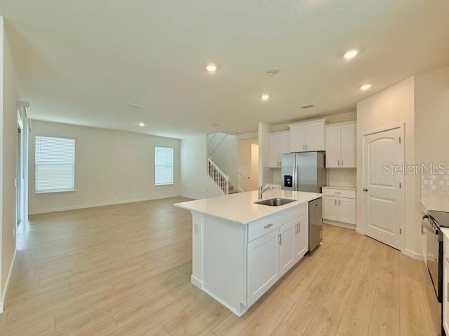 A modern kitchen with white cabinets and a center island opens to a living area — 16827 HOBE SOUND COURT, WINTER GARDEN, FL