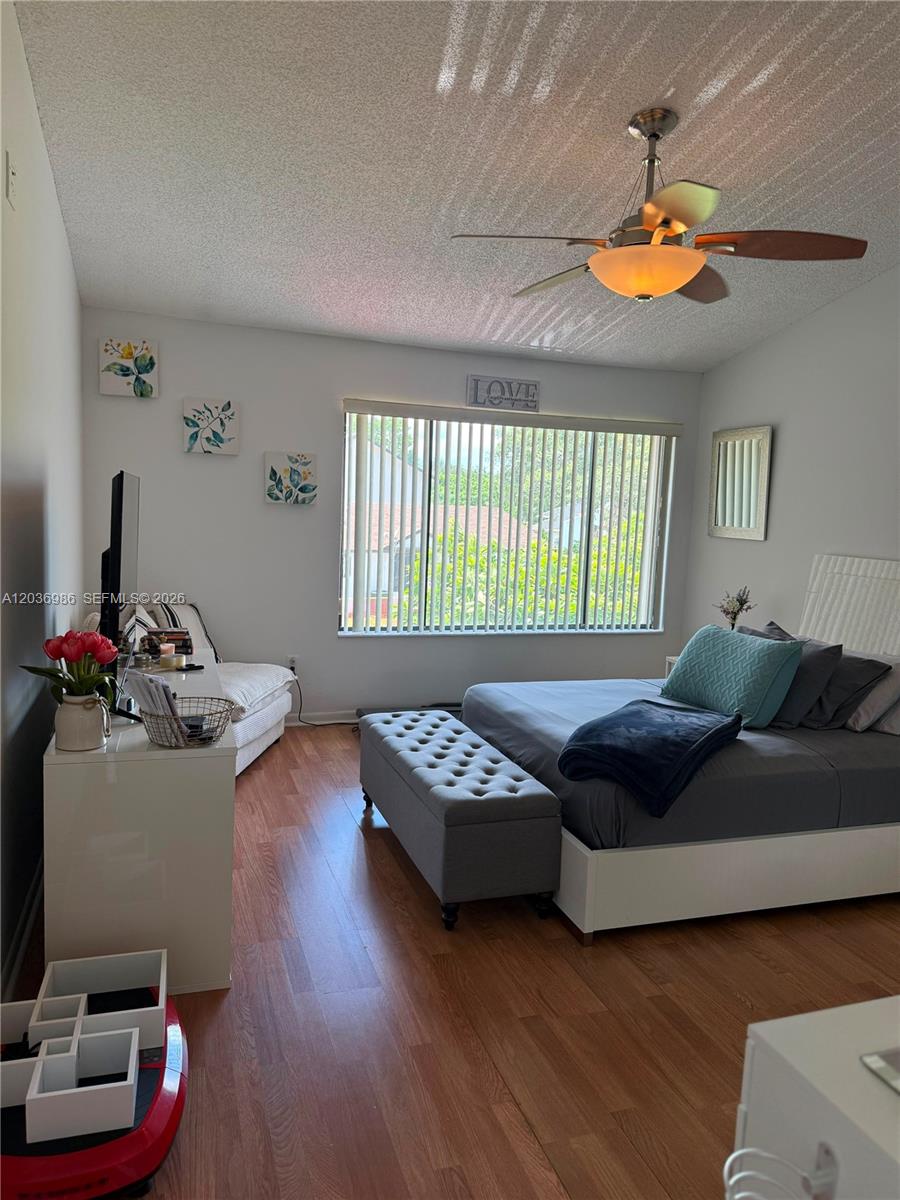 A bedroom features a bed with a gray bench, wood flooring, and a ceiling fan — 14795 SW 97th Ter # 0, Miami FL 33196, MIAMI, FL