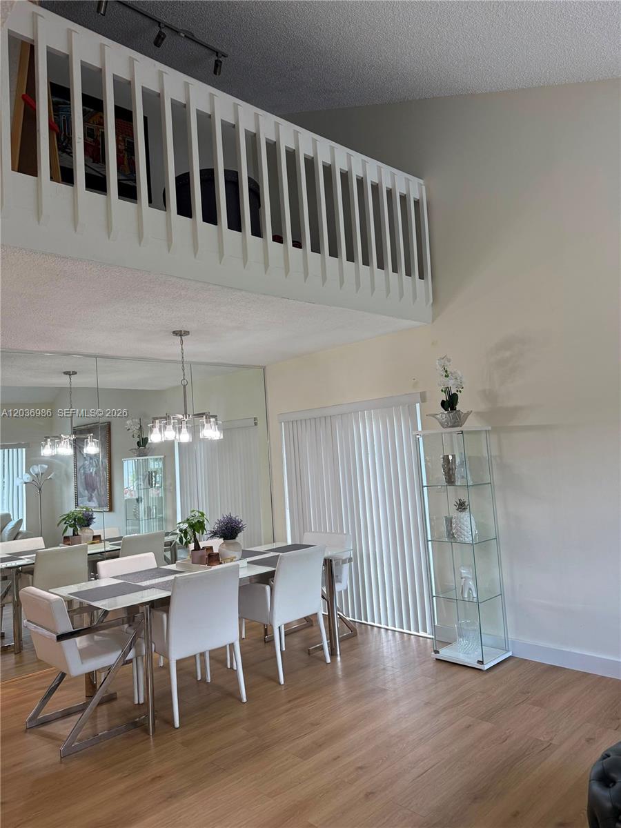 A dining area features a glass table, white chairs, a mirrored wall, and a lofted balcony — 14795 SW 97th Ter # 0, Miami FL 33196, MIAMI, FL