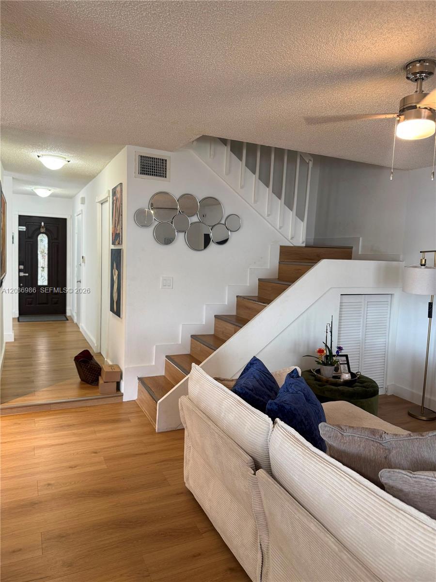 A living room features a wooden staircase, light wood flooring, and a ceiling fan — 14795 SW 97th Ter # 0, Miami FL 33196, MIAMI, FL