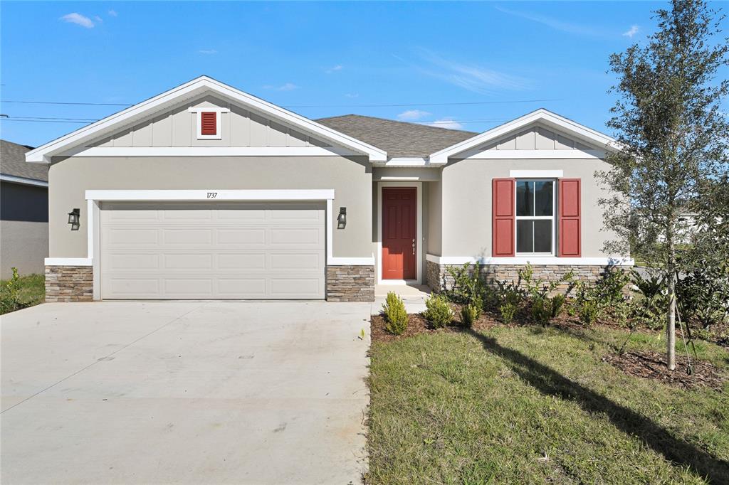 A single-story house with a two-car garage, red front door, and stone veneer accents — 1737 CARNELIAN STREET, DELAND, FL
