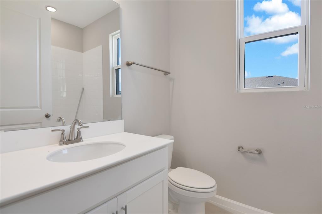 A bathroom features a white vanity, a toilet, a mirror, and a window with sky — 1737 CARNELIAN STREET, DELAND, FL