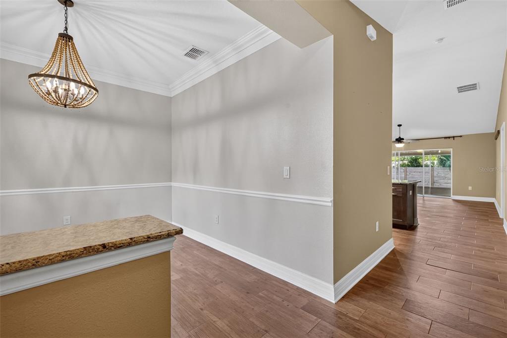 A dining area with a beaded chandelier, chair rail molding, and wood-look tile flooring — 74 N OAK AVENUE, UMATILLA, FL