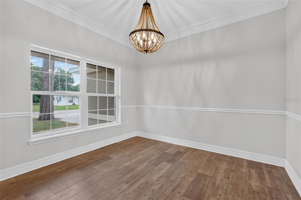 An empty dining room features light gray walls, wood-look flooring, and a beaded chandelier — 74 N OAK AVENUE, UMATILLA, FL