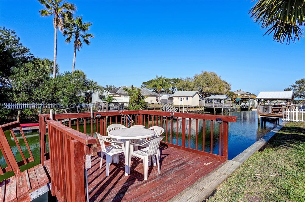 A wooden deck with a patio table and chairs overlooks a canal with boat docks — 260 VENTURA ROAD, ST AUGUSTINE, FL