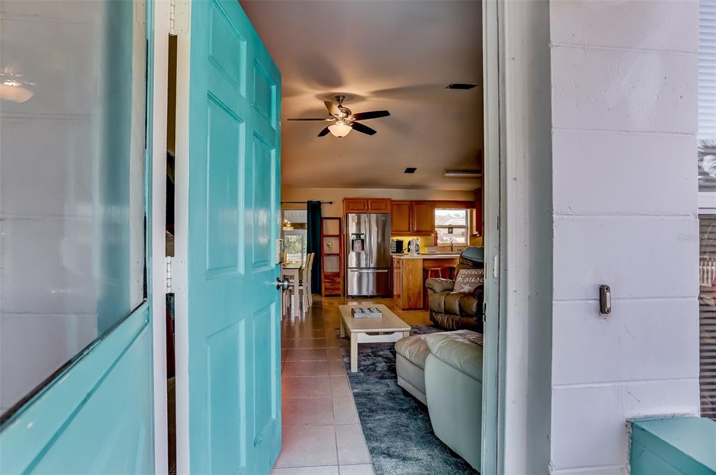 A view through an open turquoise door into a living room and kitchen area — 260 VENTURA ROAD, ST AUGUSTINE, FL