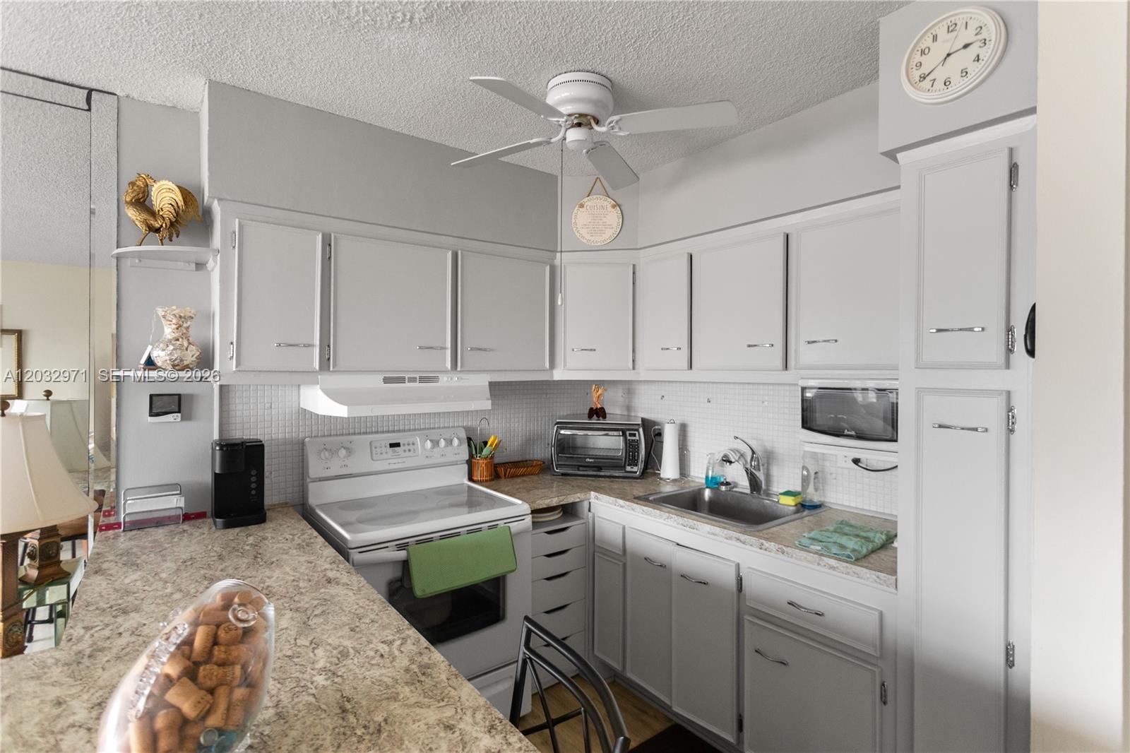 A kitchen features light gray cabinets, a white stove, a stainless steel sink, and countertops — 725 SW 11th Ave # 12, Hallandale Beach FL 33009, HALLANDALE BEACH, FL