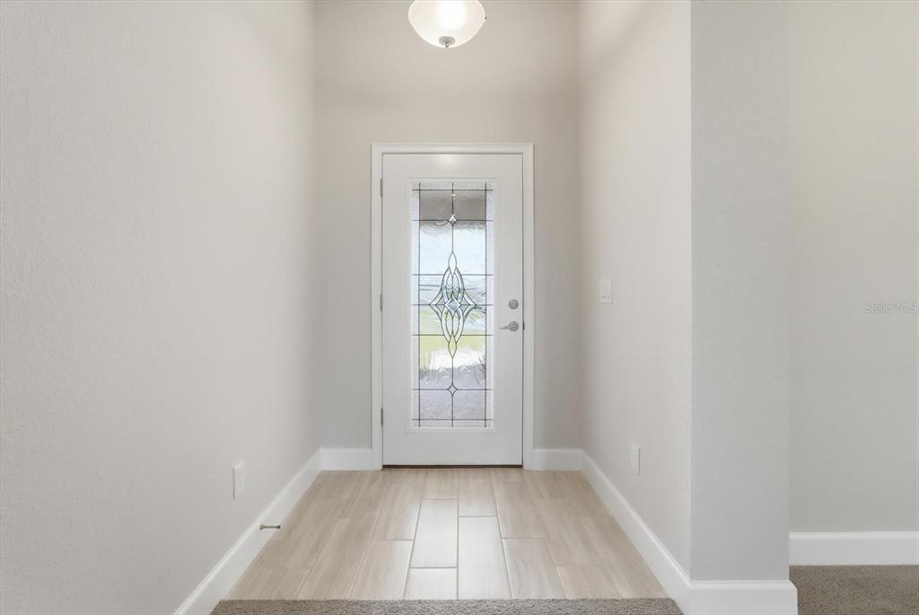 A bright entryway features light-colored wood-look tile flooring and a white door with decorative glass — 336 W REXFORD DRIVE, BEVERLY HILLS, FL
