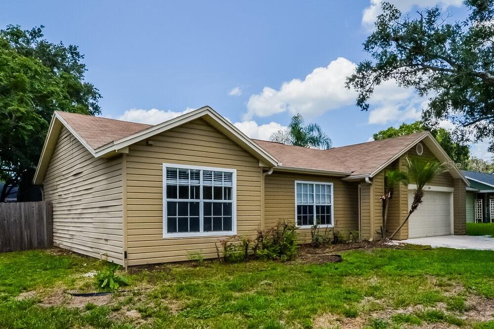 A tan, single-story suburban house with a two-car garage and a grassy front yard — 5010 LIGHTERWOOD COURT, OCOEE, FL