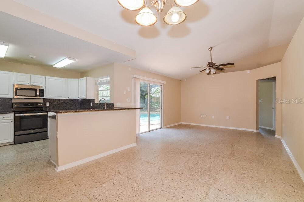 A kitchen with white cabinets and a breakfast bar opens into a tiled living area — 5010 LIGHTERWOOD COURT, OCOEE, FL