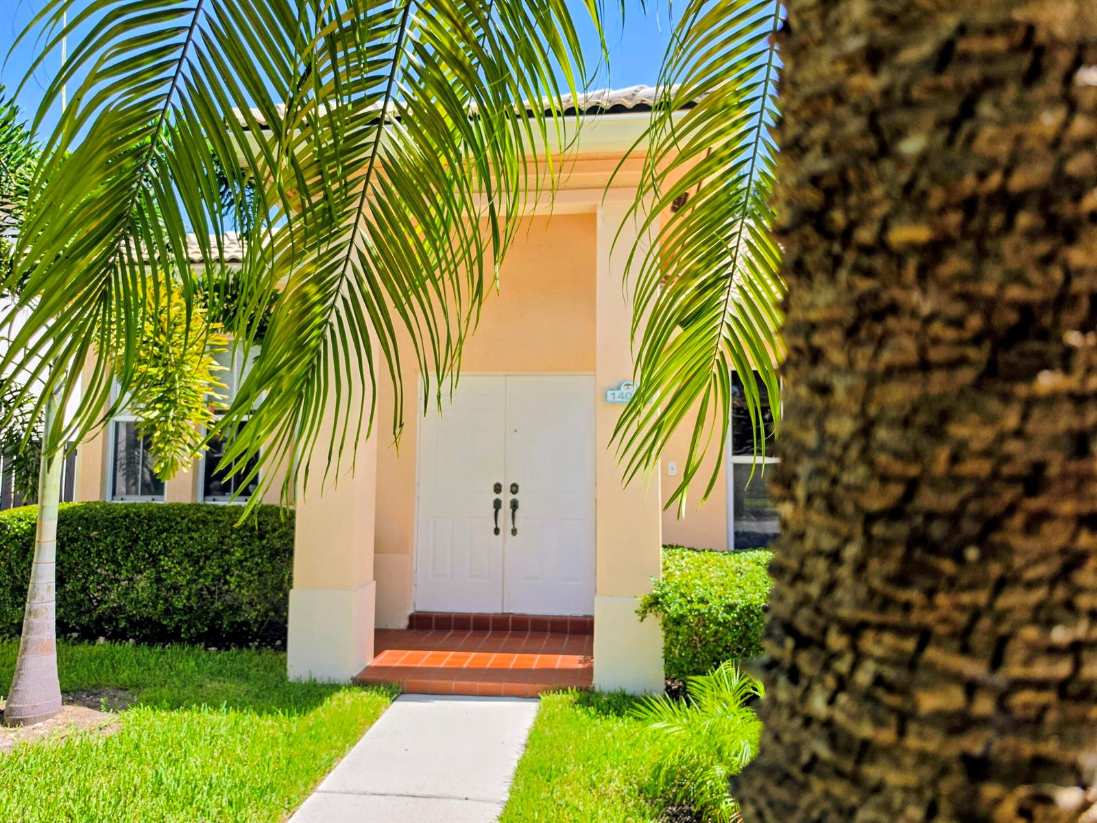 A peach-colored house exterior features a white double door entrance under a palm tree — 14013 N Cypress Cove Circle, Davie FL 33325, DAVIE, FL
