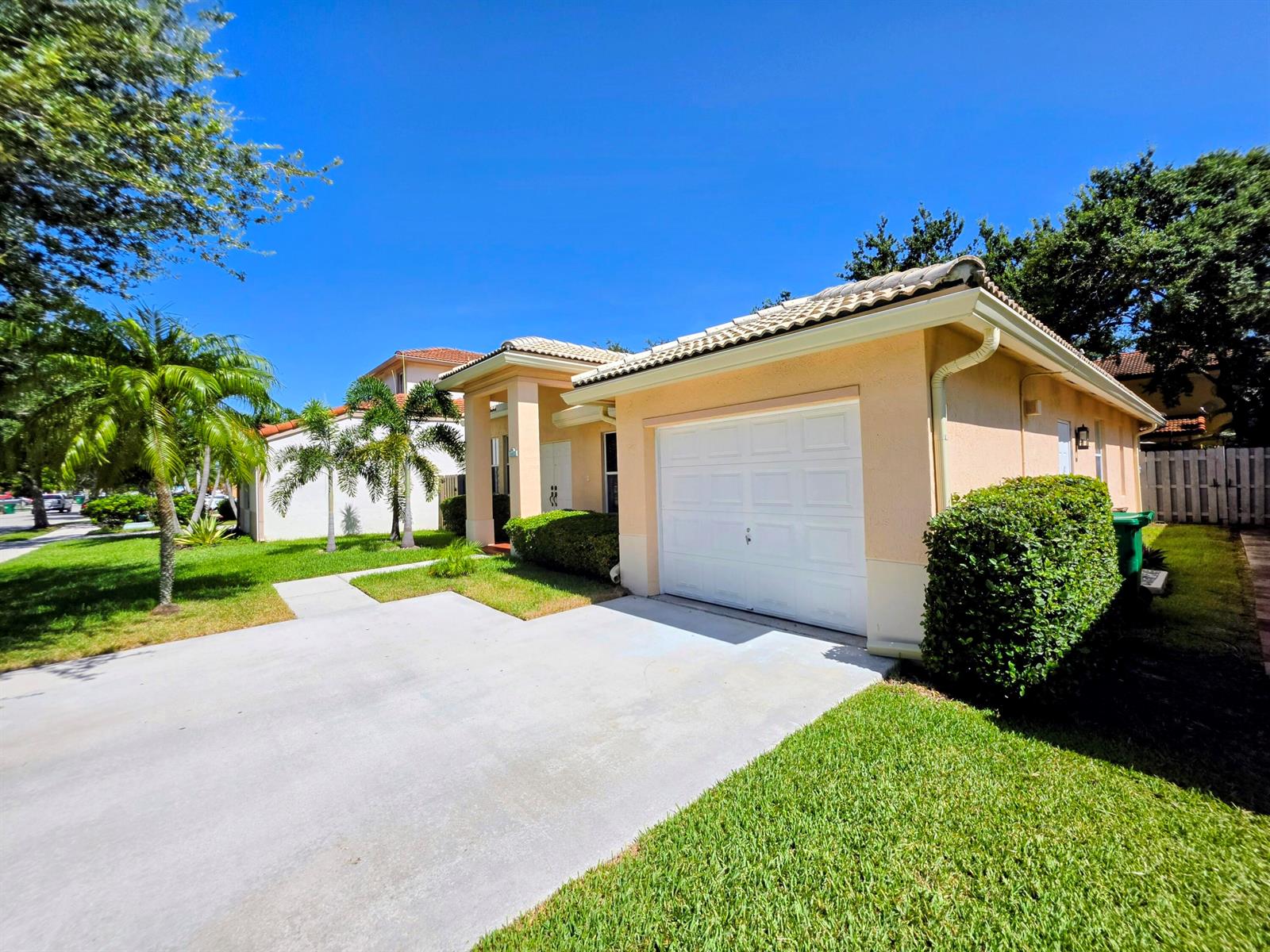 A single-story house with a beige stucco exterior, a white garage door, and a driveway — 14013 N Cypress Cove Circle, Davie FL 33325, DAVIE, FL