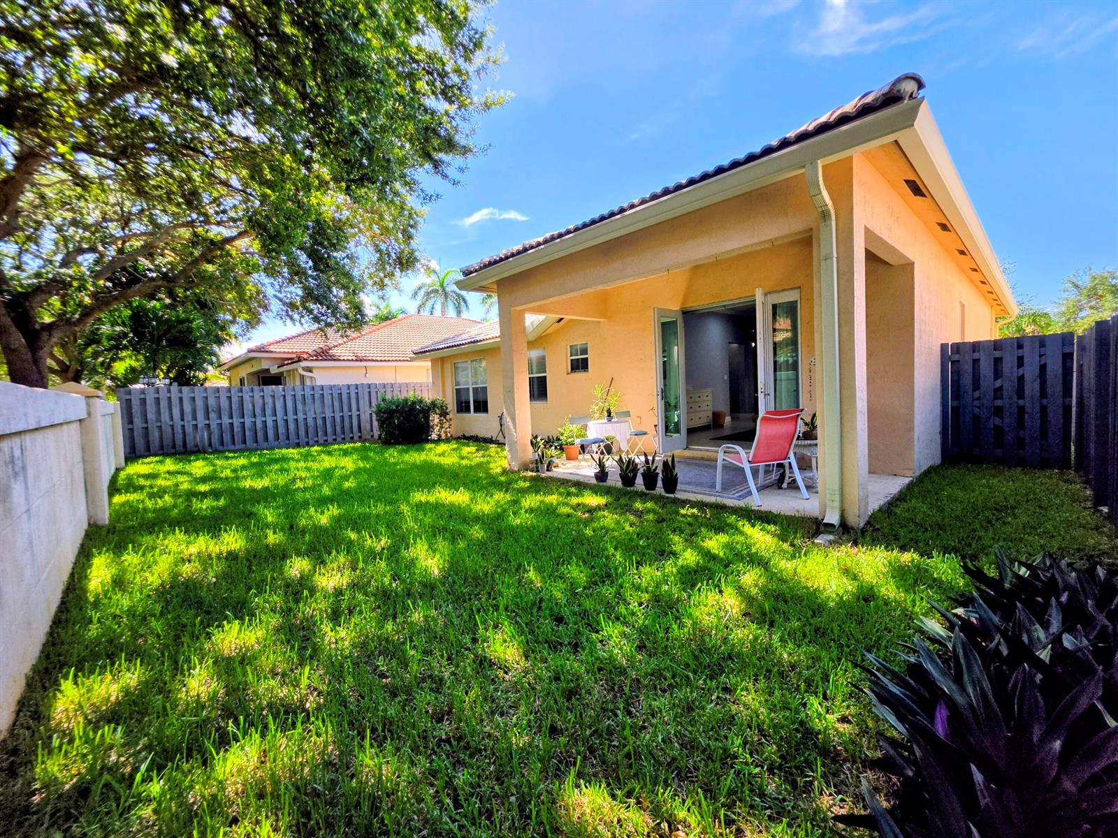 A backyard with a green lawn, a covered patio, and a light-colored stucco house — 14013 N Cypress Cove Circle, Davie FL 33325, DAVIE, FL
