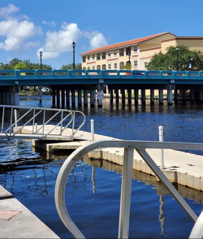 A floating dock extends into a canal beneath a blue bridge near a multi-story building — 6313 OELSNER STREET, NEW PORT RICHEY, FL