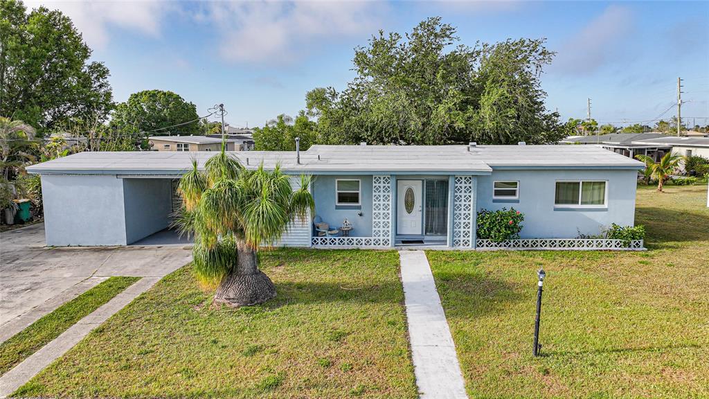 A light blue single-story house with a carport, a palm tree, and a concrete walkway — 21249 HIGGS DRIVE, PORT CHARLOTTE, FL