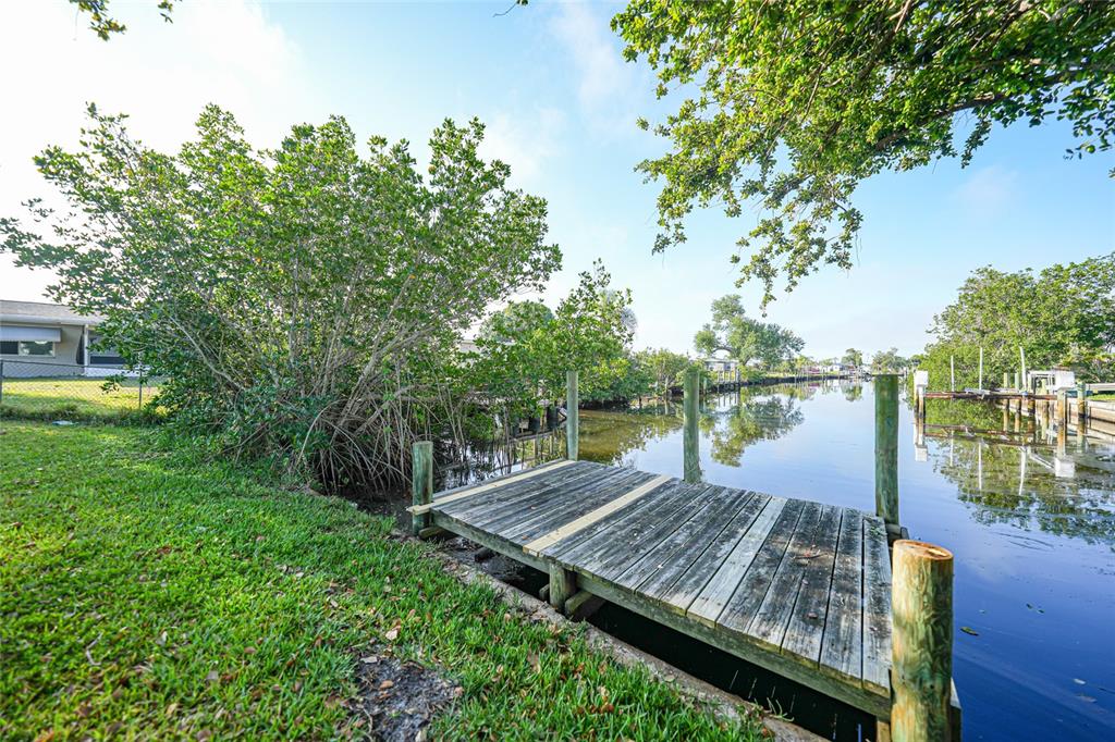A wooden dock extends from a grassy lawn into a canal lined with mangrove trees — 21249 HIGGS DRIVE, PORT CHARLOTTE, FL