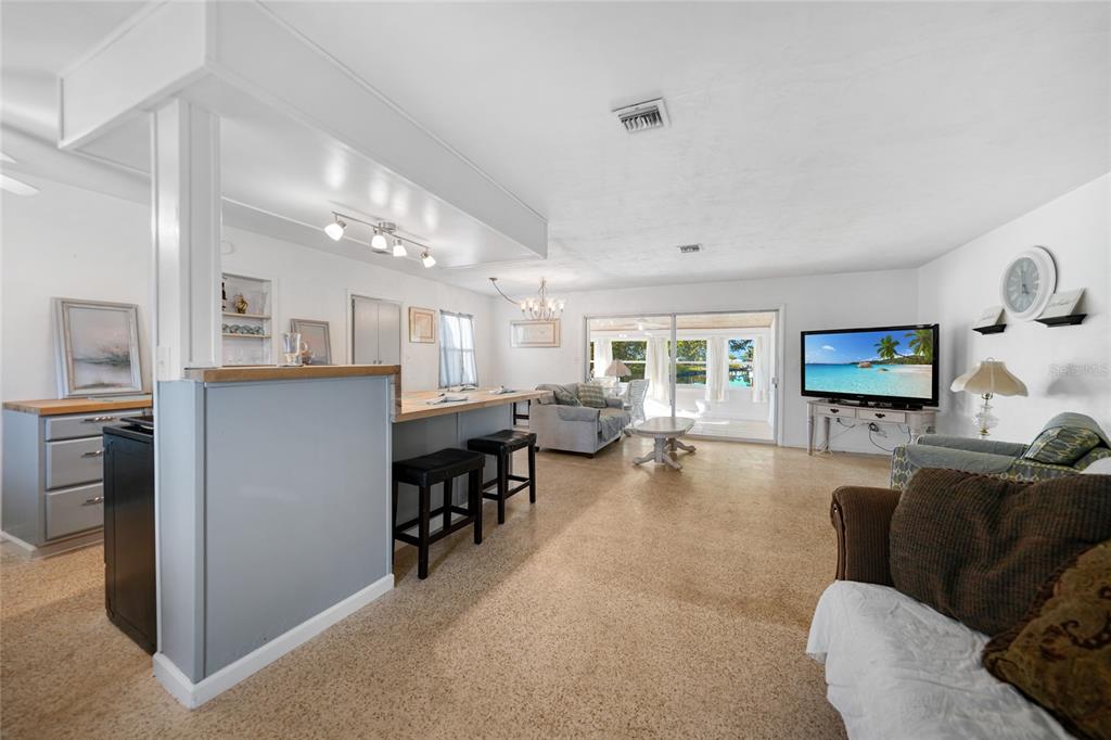 An open-concept living area features a kitchen island, dining space, and a view of a sunroom — 21249 HIGGS DRIVE, PORT CHARLOTTE, FL
