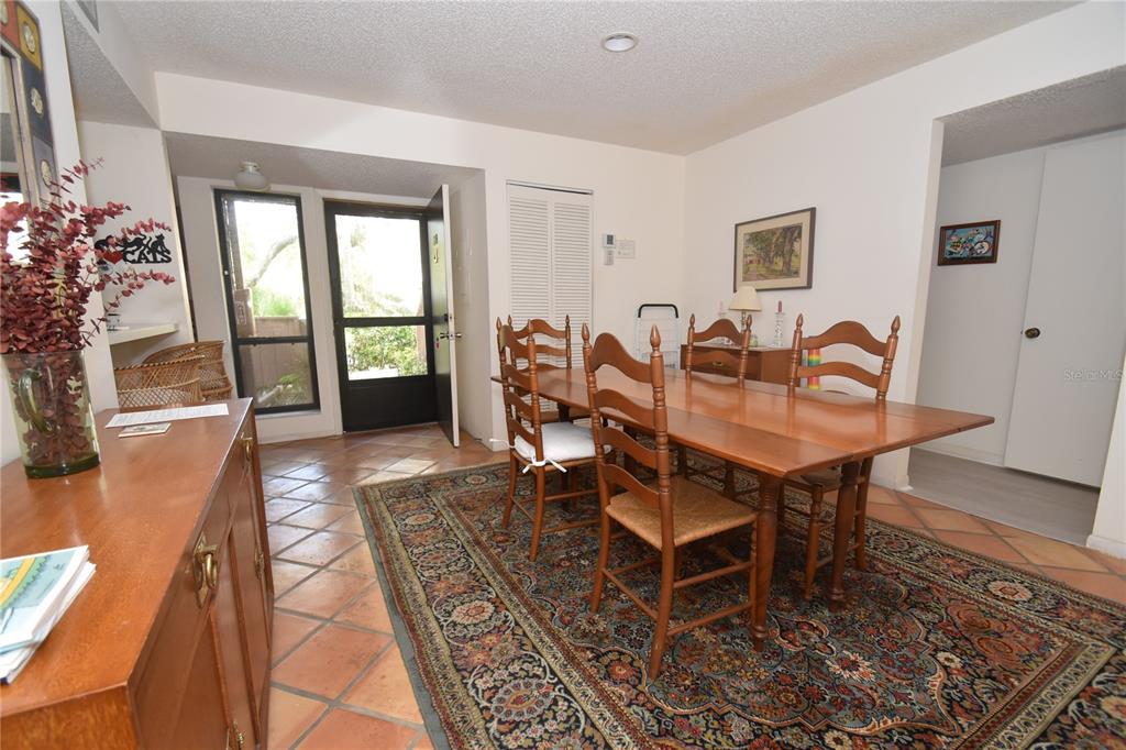 A dining room features a wooden table, chairs, a patterned rug, and terracotta tile flooring — 1626 BROOKHOUSE DRIVE UNIT BR137, SARASOTA, FL