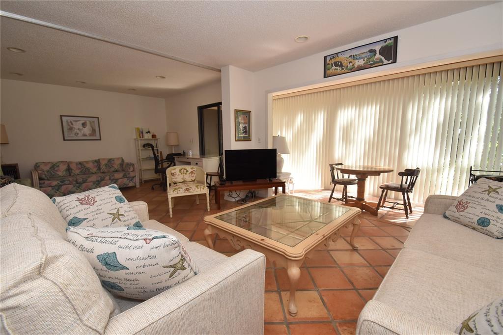 A living room features light-colored sofas, a glass coffee table, and terracotta tile flooring — 1626 BROOKHOUSE DRIVE UNIT BR137, SARASOTA, FL