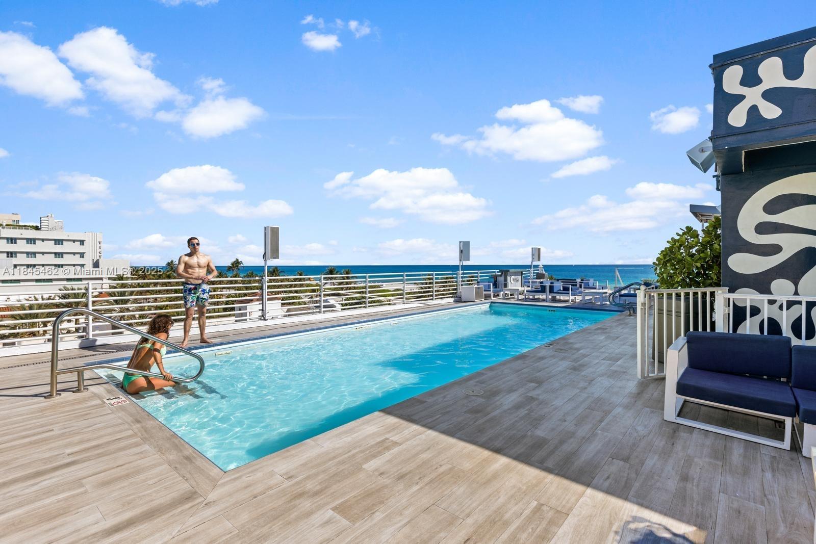 A rooftop swimming pool overlooks the ocean with a wooden deck and lounge seating — 1024 Ocean Dr # A207, Miami Beach FL 33139, MIAMI BEACH, FL