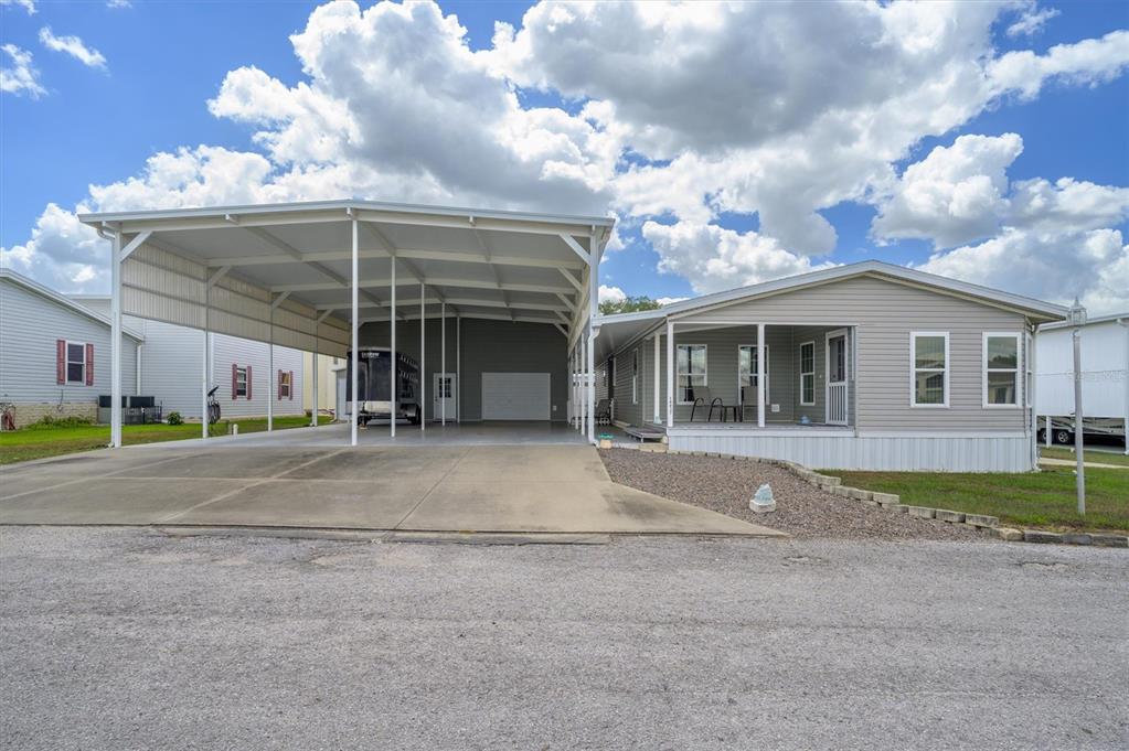 A manufactured home with a large attached metal carport and a front porch — 10027 EQUITY AVENUE, DADE CITY, FL