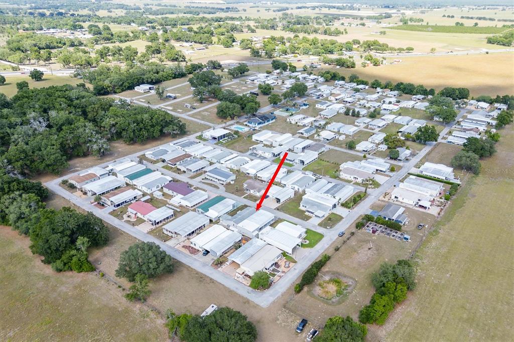 An aerial view shows a mobile home community with a red arrow pointing to a unit — 10027 EQUITY AVENUE, DADE CITY, FL