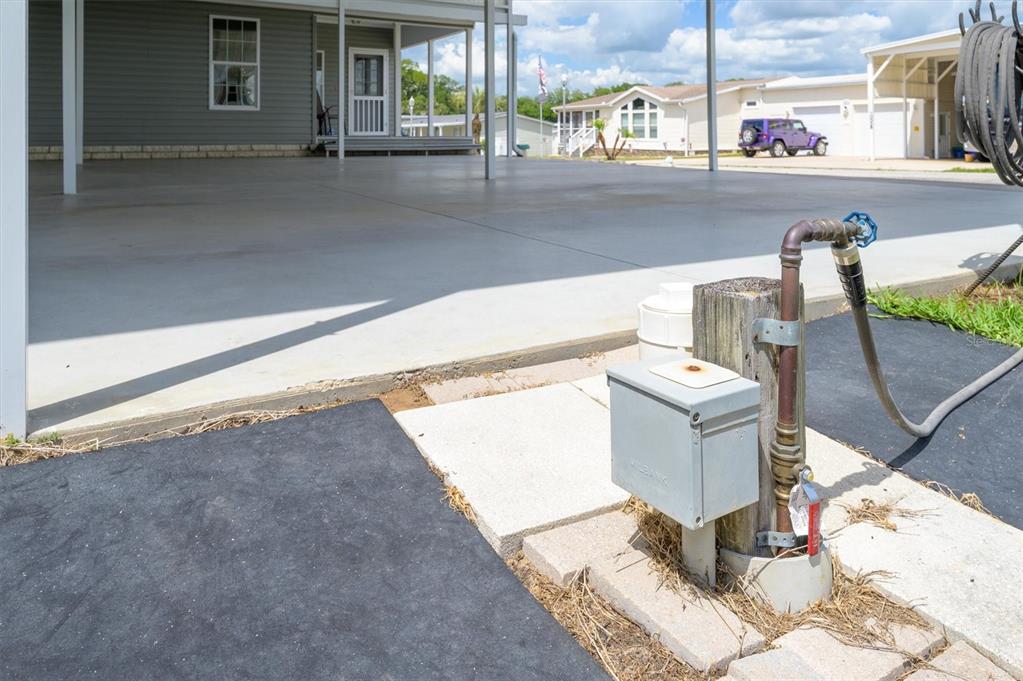 A concrete carport area sits next to a utility post with an electrical box and spigot — 10027 EQUITY AVENUE, DADE CITY, FL